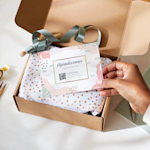 Um cliente segura um postal personalizado de agradecimento entregue com uma caixa de presente.