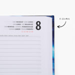 Um grande plano de uma agenda com capa dura aberta. Inclui uma nota que indica a existência de oito idiomas nas páginas.