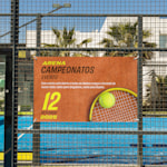 Uma lona publicitária standard para um torneio de ténis, pendurada pelos ilhós na vedação de um campo de ténis.