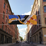 Uma rua da cidade com uma lona publicitária personalizada de dupla face a promover um concerto de jazz.
