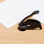 Um carimbo de alto relevo ao lado de material de escritório personalizado, exibindo uma impressão em alto relevo a condizer no papel.