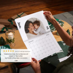 Ett par händer håller en specialdesignad väggkalender som visar ett foto av en mamma och en bebis.