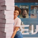 A person carrying a big stack of mailing boxes promoting a beauty & apparel brand.