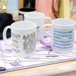 Three white mugs featuring artwork by @artofbrentos