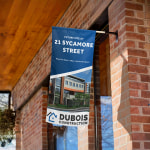 A wall flag promoting a construction business, displayed at the corner of a building.