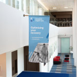 A wall mount flag promoting urgent care services, mounted indoors.