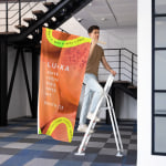 A wall flag promoting a wellness brand, being installed by a man.